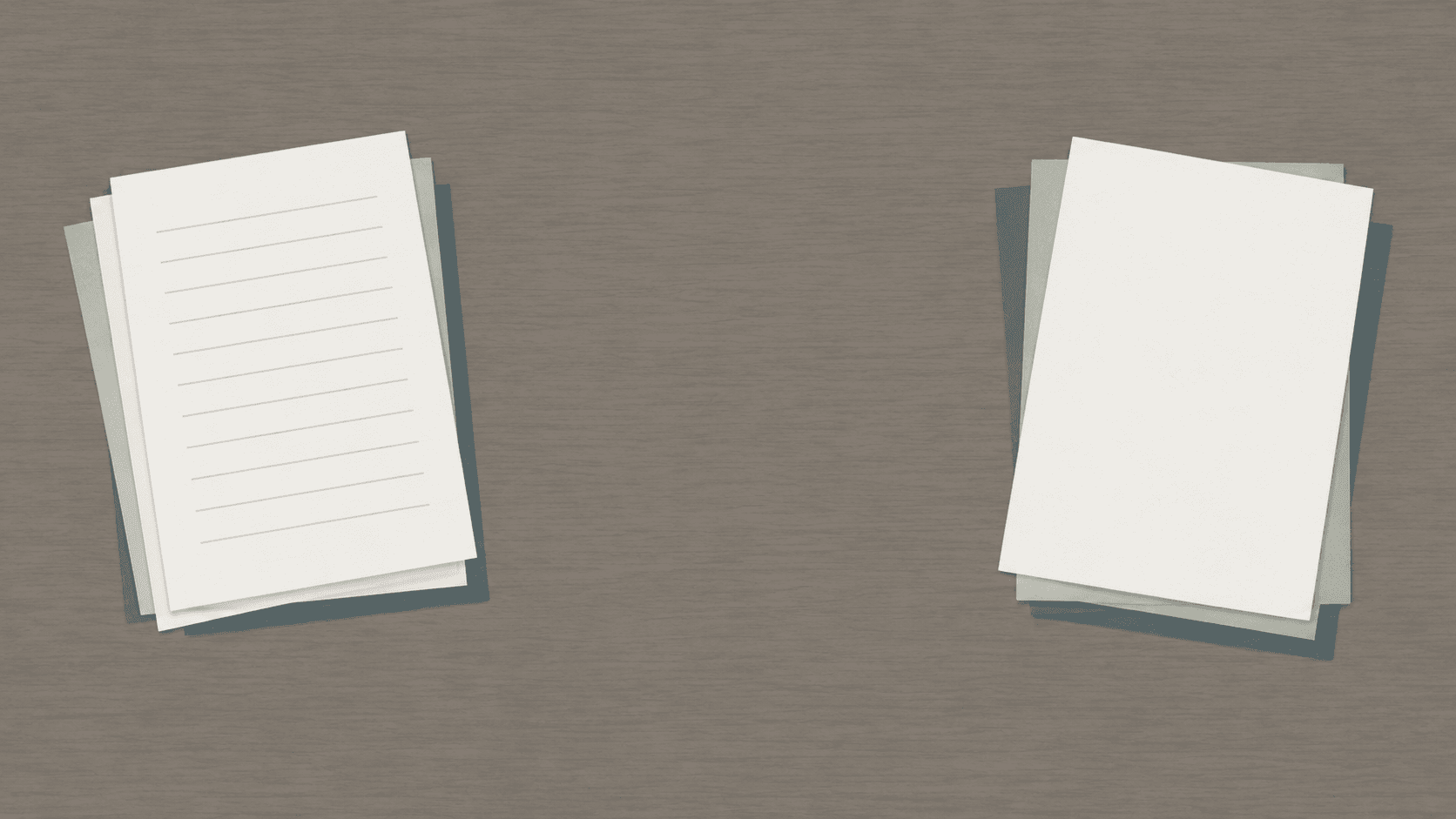 Two separate piles of blank documents placed apart on a wide bare desk, seen from above.