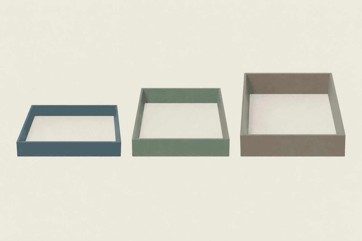 Three plain empty card trays of increasing depth standing side by side on a flat pale surface.